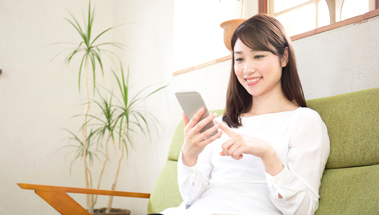 ソファでスマホを眺める女性
