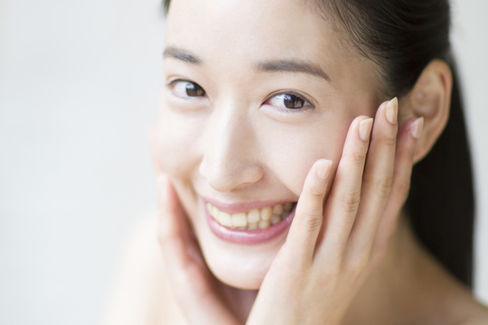 頬を触る笑顔の女性