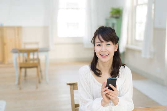 スマホ持つ笑顔の女性