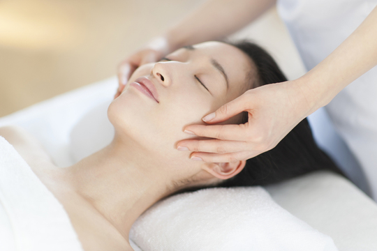 頬をマッサージされている女性